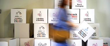 Cajas apiladas que muestran logos y lemas de Hispack